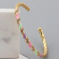 Detail of gold-plated twisted bangle with colorful enamel sections and inlaid crystals - Colorful