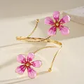 Detailed close-up of a vintage pink enamel flower arm cuff in a polished gold finish. - Pink