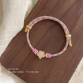 Woven red rope bracelet featuring a purple flower charm and colorful braided accents - Purple Flower Multicolor Braided Bracelet