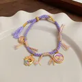 Handwoven purple rope bracelet with golden fish lucky charm and floral enamel pendant - Purple