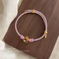 Hand-woven colorful red rope bracelet with a gold enamel elephant pendant and glass beads - Pink/Blue