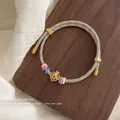 Handwoven multicolored silk cord bracelet with floral enamel charm and gold clasp - Blue/Yellow