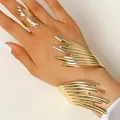 Gros plan sur l'ensemble de bijoux sculpturaux abstraits dorés avec bracelet et bague - Parure Bracelet Bague Sculpture Lignes Abstraites / Or