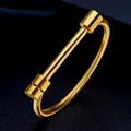 Primo piano di un bracciale in acciaio al titanio dorato su sfondo nero materico - Taglia unica / Oro (Stile Ferro di Cavallo)