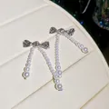Elegant silver bow earrings with long dangling white faux pearl strands for women - Silver