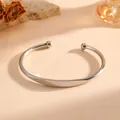Close-up van een minimalistische open armband van roestvrij staal in gepolijst zilver - Gladde Bolstijl (S710) / Staalkleur