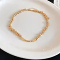 Close-up of irregular gold-tone beads and central curved bar on a fashion necklace - Gold