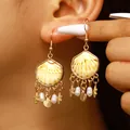Détail de boucles d'oreilles coquillage dorées style bohème avec étoiles de mer et perles - Gland de Coquillage Doré (10443)