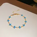 Detailaufnahme eines vergoldeten Armbands mit blauen Harzblumen und funkelnden Steinen. - Mehrlagiges Blumenarmband (1#) / Gold-Blau