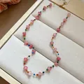 Detail of a dainty stainless steel necklace with pink and colorful glass beads on a tray - Pink