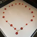 Dettaglio di una collana dorata con perle di vetro rosse in una confezione regalo. - Collana #18 - Oro - Rosso