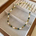 Dettaglio macro di una collana di perle in acciaio inossidabile con perle di vetro colorate - Collana N. 22 - Marrone - Bianco - Oro