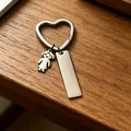 Detail van roestvrijstalen hart sleutelhanger met meisje bedel en blanco DIY tag - Meisjes Charms / Staalkleur