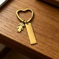 Detailopname van een gouden hartvormige sleutelhanger met een meisjesbedel en tag - Meisjes Charms / Goud