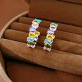Primo piano di orecchini a cerchio in argento con zirconi colorati in una scatola marrone - Argento Multicolore