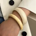 Detail of cream white and ivory resin bangles with irregular marbled texture on wrist - 2-Piece Set / Cream White And Ivory Yellow