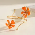 Detail shot of golden spiral arm cuff featuring vibrant orange enamel flower motifs - Floral (HB5775) / Orange