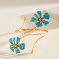 Detail view of an elegant gold metal arm cuff with turquoise enamel flower charms. - Floral (HB5775) / Blue