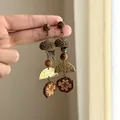 Close-up of ethnic Maillard style earrings with acorn, wood beads and metal tassels - Silver Earring Post Style