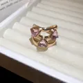 Close-up of a high-end gold ring featuring three sparkling pink triangular gems - Multi-Layer Triangle Style / Pink