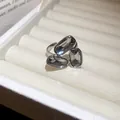Detailopname van een elegante zilveren open ring met drie grijze gefacetteerde stenen - Drie-Steen Driehoekstijl / Grijs