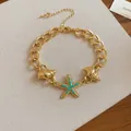 Close-up of gold conch and turquoise beaded starfish charms on a summer style link bracelet. - 54# Bracelet / Gold-Blue