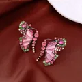 Detailed close-up of vintage pink and green butterfly stud earrings on brown fabric. - Stud Earrings (Silver Post - Rose Red - Green)