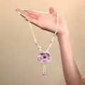 Dettaglio di una collana di fiori intrecciati viola fatta a mano con perline colorate - Viola