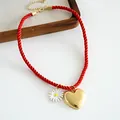 Detailed view of a red twisted rope necklace featuring a gold heart and daisy charm - Red Heart Flower Style (HN12001) / Red Heart Flower
