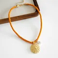 Close-up detail of a resort style orange rope necklace with gold textured pendant and pearl - Orange Round Style (HN12005) / Orange Round