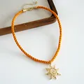 Macro view showing the texture of the orange braided cord and golden sun pendant - Orange Sun Style (HN12003) / Orange Sun