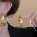 Detail view of large gold brushed hoop earrings with a minimalist and elegant design - Brushed Gold (Silver Post)