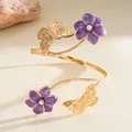 Close-up of golden armlet featuring purple enamel flowers and delicate butterflies - Purple