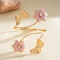Detailed view of elegant gold arm cuff with pink enamel flowers and pearl butterfly motifs - Pink