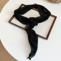 Gros plan sur l'écharpe collier en mousseline noire avec détail de rose en tissu - Ensemble deux pièces (accessoire de cheveux et de cou) / Noir