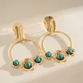 Nahaufnahme von goldenen Creolen mit türkisfarbenen Blumen und Metallsteckern - Silberner Ohrstecker - Gold - Blau