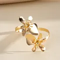 Gedetailleerd zicht op een gouden metalen armring met elegante bloemmotieven en goud. - Goud
