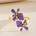 Macrodetail van een gouden armband met twee prachtige paarse geëmailleerde bloemen. - Paars