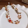 Collana in ceramica marrone con perle d'ambra e ciondoli a fiore in bronzo - Oro