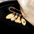 Detailed macro shot of a unique gold-toned safety pin brooch with artistic facial charms. - Facial Features Pin Style (HP1010)