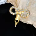 Detail view of a gold-toned bow brooch with zircons and a fountain pen nib pendant - Bowknot Pen Nib Style (HP1010) / Gold