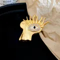 Close-up view of artistic gold metal eye brooch with sparkling clear zircon stone inlay - Palm Eye Style (HP1010) / Gold