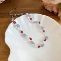 Detailed close-up of a handmade crystal beaded flower necklace on a white shell plate - White-Red-Blue (16#)
