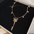 Elegant gold butterfly key necklace with zircon accents and delicate flower charms - Necklace / Gold