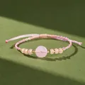 Primo piano di bracciale intrecciato rosa fatto a mano con calcedonio tondo e perline oro - Rosa