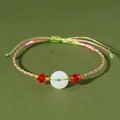 Dettaglio di bracciale in cordino colorato intrecciato a mano con ciambella in calcedonio - Rosa-Bianco