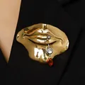Close-up van een gouden surrealistische lippenbroche met uniek piercingdetail op stof - 01 KC Goud (Rode Strass)