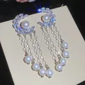 Detailopname van elegante zilveren bloemoorbellen met trapsgewijze parels en kristallen. - Stijl 36 (HE32568)