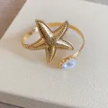 Detailansicht des goldenen Seestern-Armreifs mit strukturierter Oberfläche und Perle - Seesternform (Mit Perle) / Gold