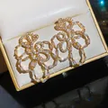 Elegante goudkleurige bloem oorknopjes bezet met sprankelende witte zirkonia steentjes - Stijl 62 (HE32568)
